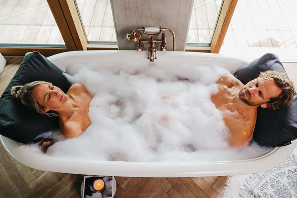 Mann und Frau entspannen in der Badewanne mit Badesofa im Rücken